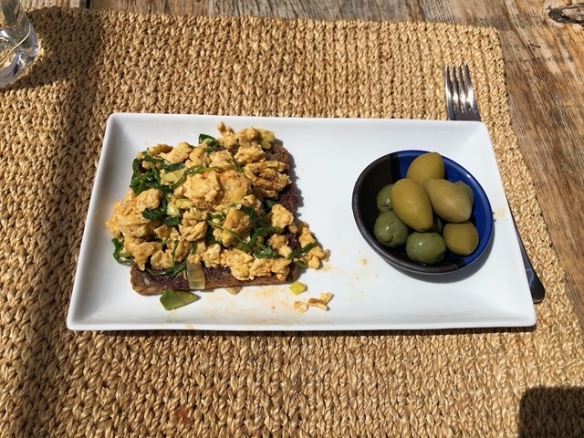 Lunch of scramble with greens and tapenade on rye, and green olives