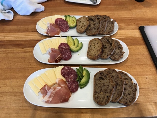 Charcuterie plate with walnut sourdough, prosciutto, salami, cheese, and avocado