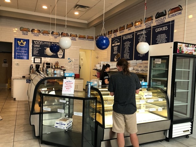 At the cannoli shop, with the flavors listed on the wall