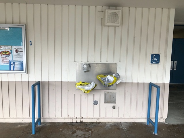 Water fountains are covered in plastic and caution tape