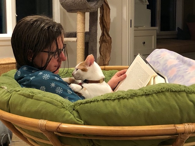 Lela reading with Gizmo, in her pajamas in the papasan chair