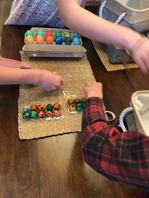 All three kids putting the eggs in their containers for safekeeping